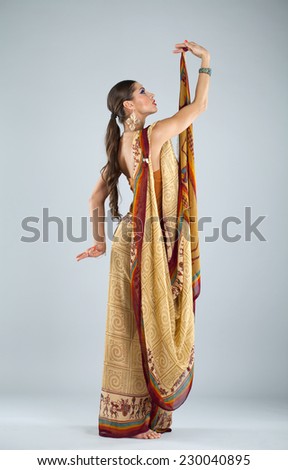 Full body cheerful traditional Asian Indian woman in indian sari, isolated on gray background