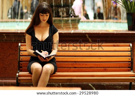 The young girl sitting on a bench reads the book