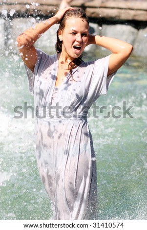 young beautiful caucasian girl playing at an outdoor water fountain
