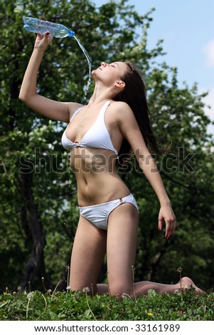 young woman pours over herself water from a bottle