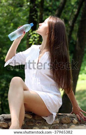 Young woman drinks mineral water  in park