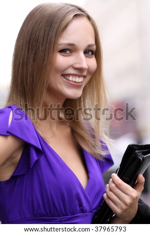 Portrait of a young woman with a bag  smiling on urban background