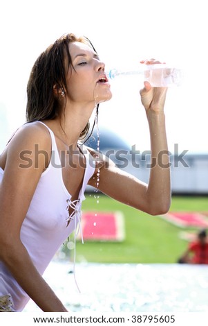 Attractive girl drinking water in city fountain