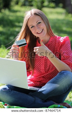 A young girl with a laptop and a credit card at summer park?