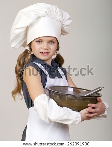 Little girl cook whips whisk eggs in a large plate, isolated on white background