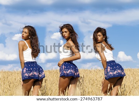 Beautiful sexy young women in blue skirt in a wheat golden field