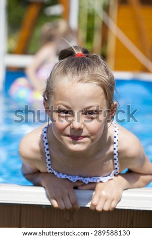 Happy little Girl in blue bikini swimming pool