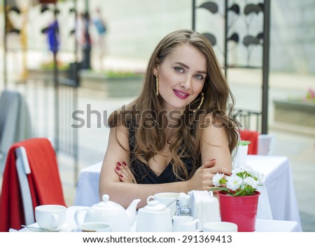 Happy Beautiful young blonde woman sitting in a coffee shop and drink tea