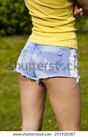 Part of the body, torn blue jeans shorts for women on the background summer street