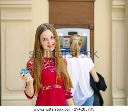 Blonde lady using an automated teller machine . Woman withdrawing money or checking account balance