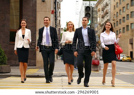 Full length portrait of a young Five successful business people crossing the street in the city center