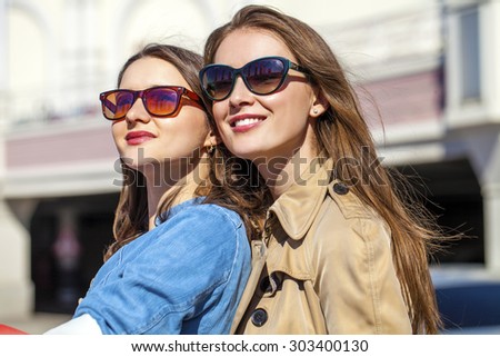 Two young beautiful girlfriends in sunglasses in the summer city