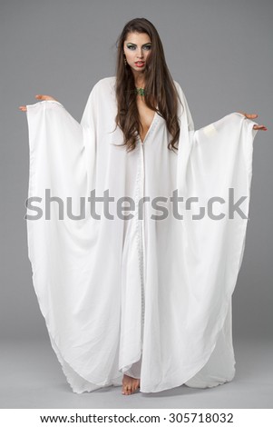 Beautiful young woman in a white tunic Arabic, on gray background