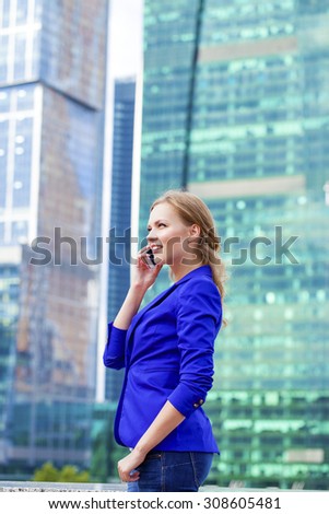 Beautiful young blonde in a blue jacket calling by phone