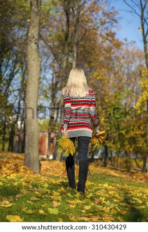 Young Beautiful blonde woman walks in autumn park