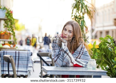 Portrait of a beautiful young woman sitting in a cafe on the street