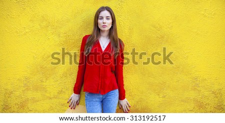 Sexy young brunette woman, against the background of the yellow wall