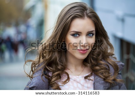 Portrait close up of young beautiful brunette woman, on spring street background