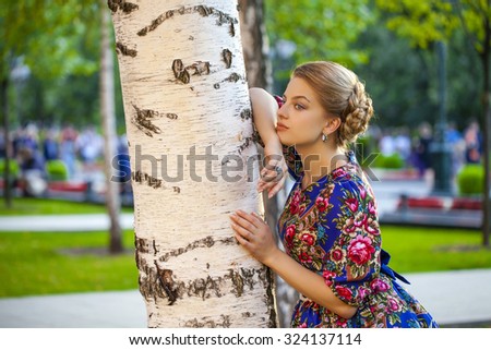 Portrait of Beautiful blond woman on a tree in autumn park