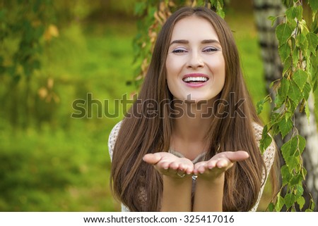 Blow kiss, young caucasian female haired model in autumn park
