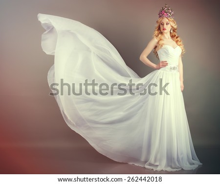 Bride in flying wedding dress in the studio on a gray background