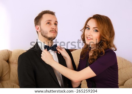 Pretty girl adjusting the bow tie.woman tying a bow tie guy