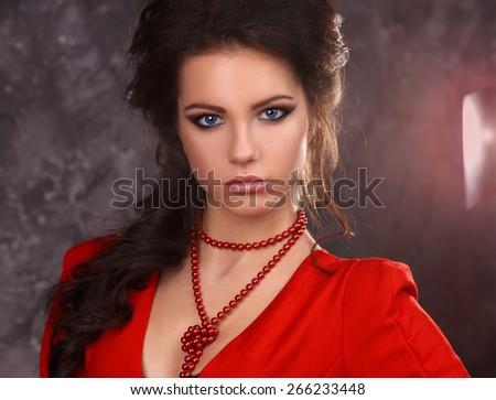 beauty portrait of a beautiful sexy brunette in a red dress on a gray background.flash of light on the background
