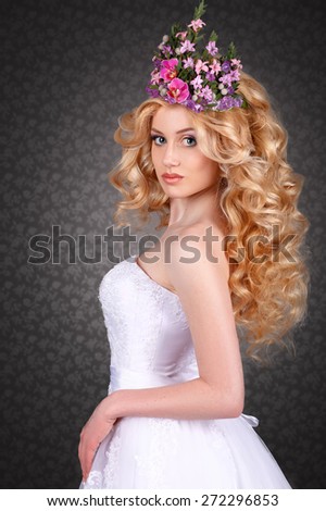 bride in white dress with perfect makeup and a crown of flowers on her head.curly-haired blonde with flowers in her hair
