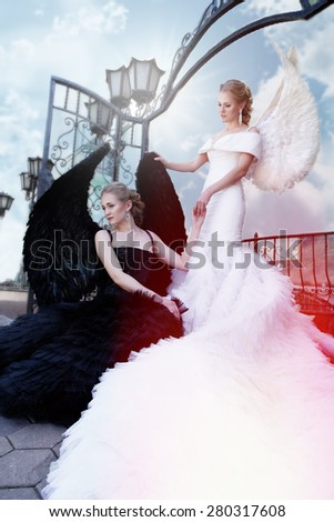 two angels. white and black angels.good and evil. black angel standing over white angel