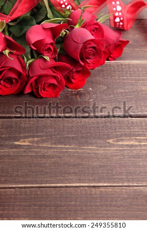Valentine background of  red roses and ribbon on wood. Space for copy.