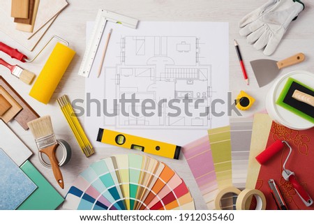 Decorator work table with house project, paint brush and painting roller, color swatches and tools, top view Foto d'archivio © 