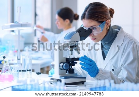 Young scientists conducting research investigations in a medical laboratory, a researcher in the foreground is using a microscope ストックフォト © 