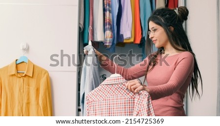 Young happy woman holding two shirts and comparing them, she is choosing what to wear Stock foto © 