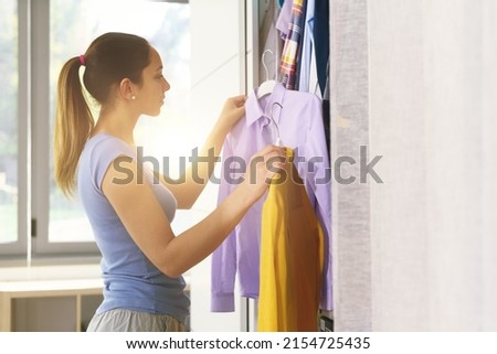 Woman comparing two shirts in her wardrobe, she is choosing which one to wear Stock foto © 