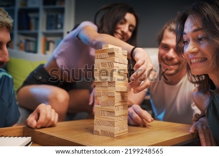 Similar – Image, Stock Photo Excited girl playing jenga game with her mom in play room. Girl removing one block from stack and placing it on top of tower. Game of skill and fun. Family time