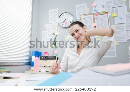 Tired female white collar with stiff neck working at desk.