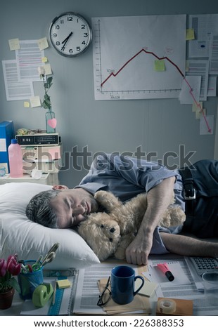 Office worker sleeping at workplace with teddy bear and pillow.