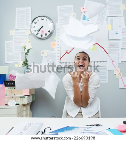 Angry businesswoman in office throwing paperwork in air and shouting.