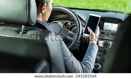Young female driver using touch screen smartphone and gps navigation in a car.