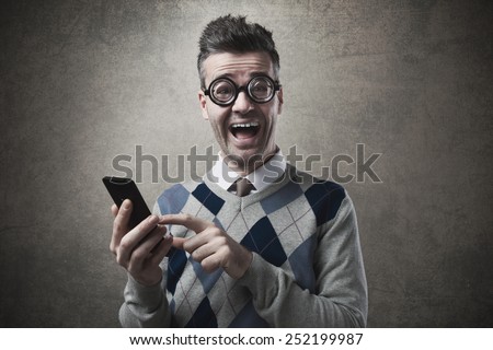 Cheerful funny guy holding a touch screen smartphone and staring with mouth open at camera