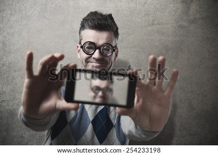 Funny guy with glasses taking a self picture with a smartphone