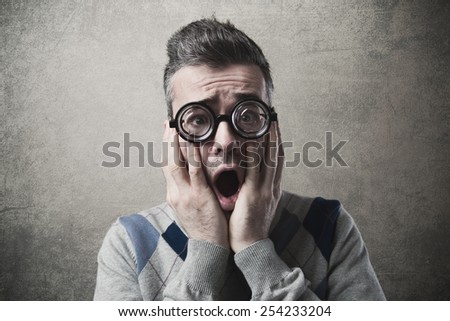 Shocked funny guy staring at camera with head in hands