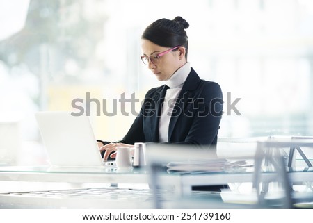 Busy elegant woman at the bar working on her computer next to a window