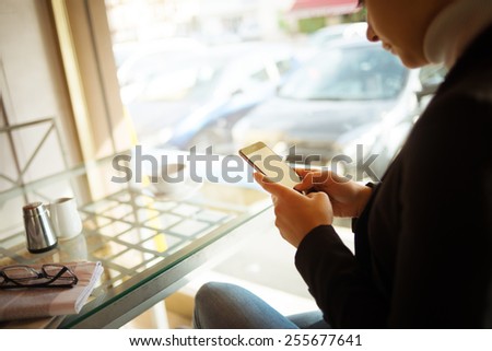 Woman having a coffee and chatting with her touch screen smart phone