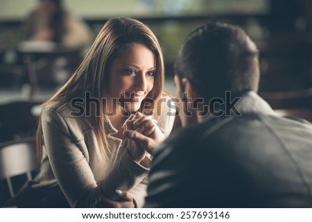 Romantic young couple dating and flirting at the bar, staring at each other\'s eyes