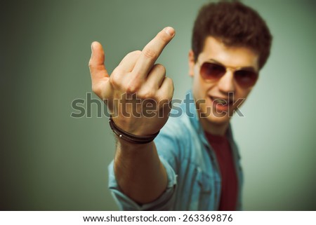 Confident smiling teenager in sunglasses showing middle finger