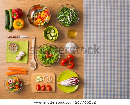 Healthy fresh vegetarian food on kitchen table with checked tablecloth on the right, top view