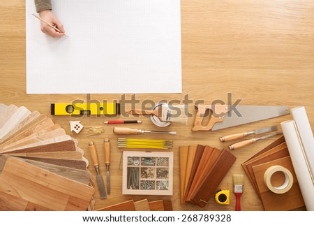 Man sketching a DIY project on a work table with construction tools top view, hobby and crafts concept