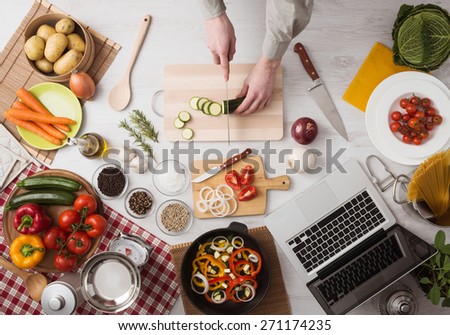 Man cooking in the kitchen and slicing vegetables on a chopping board, top view