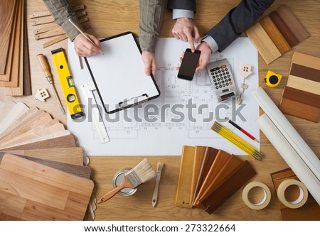 Business people working together on a building project, desktop top view with tools, wood swatches, mobile phone and blueprint